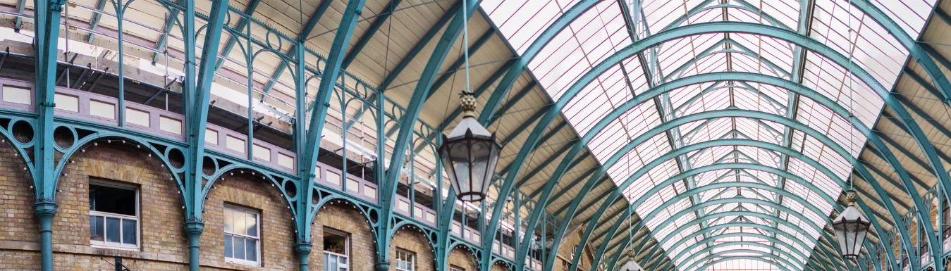 An arched ceiling with rows of teal supports and traditional style pendant lights