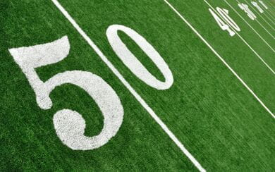 A close-up of the 50-yard line of a football field, angled to show the 40, 30, etc. yard lines