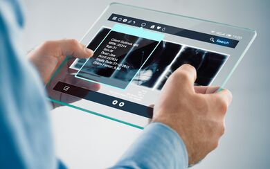 A medical professional viewing a patient's chart and diagnostic images on a clear touch-screen device