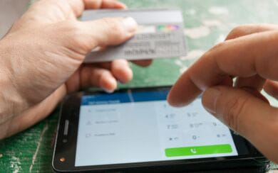 A close-up of a person accessing a mobile banking app and holding their credit card