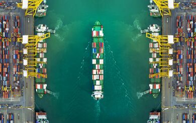 An aearial shot of a cargo ship passing through the harbour