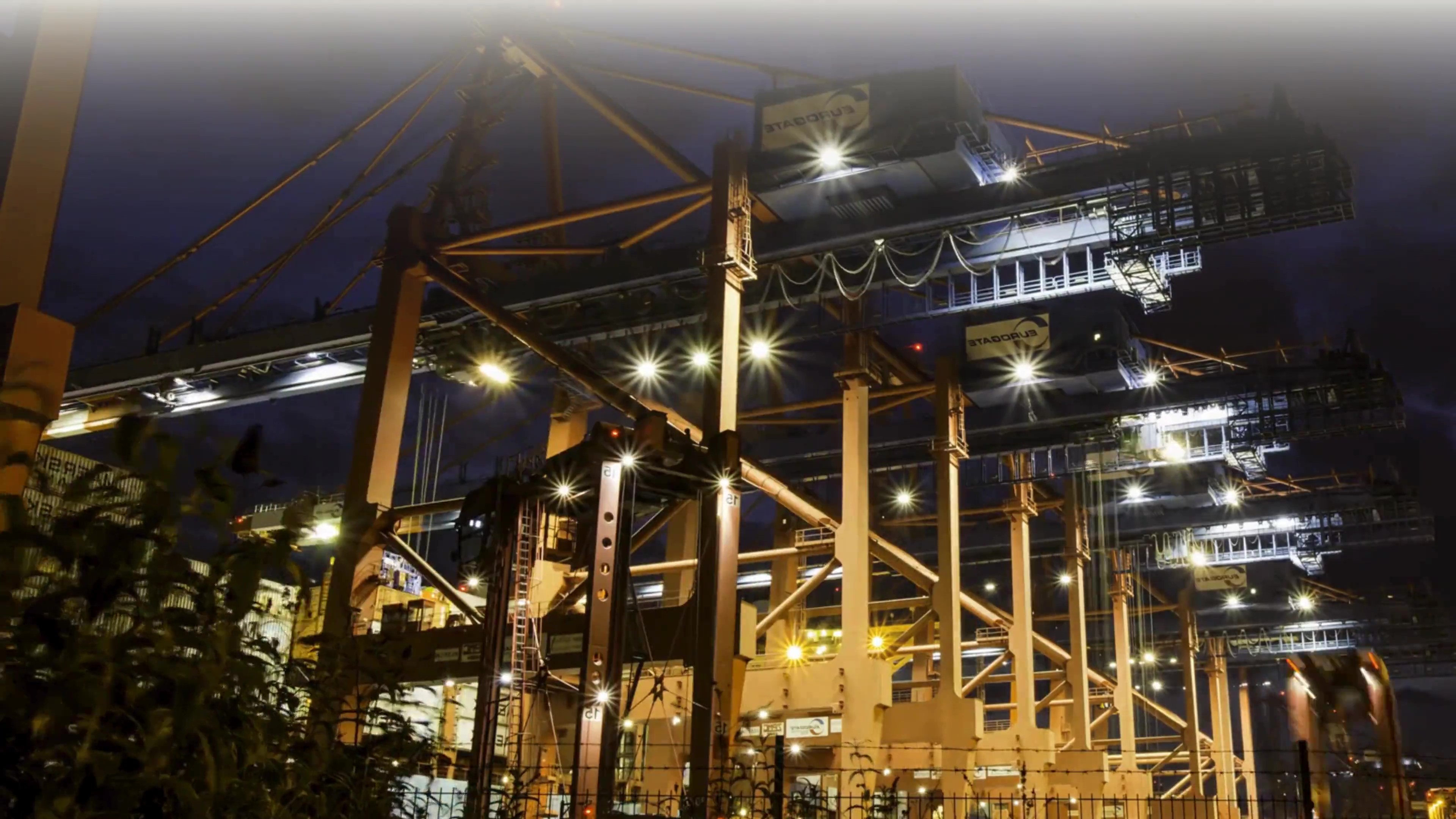Industrial port cranes and logistics infrastructure at night, representing Hogan Lovells’ Future of Manufacturing Strategic Insights on supply chains, automation, and global manufacturing transformation