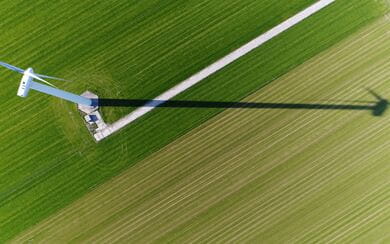 Aerial view of a wind turbine in a green field, transforming the kinetic energy of the wind into renewable electricity, contributing to a sustainable and eco-friendly power grid