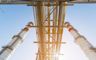 Gas turbine power plant on natural gas with chimneys of red-white color against a blue sky on a sunny day