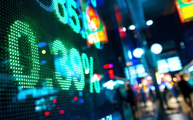 A close reflection of a stock market chart shining brightly in a city at night