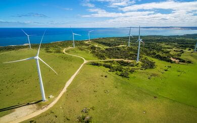 A bright, sunny day in Australia with a wind farm positioned on a mountain range; a symbol of energy and natural resources.